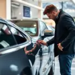 Achat d'une voiture d'occasion - homme examinant un véhicule d'occasion