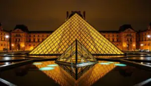 Pyramide du Louvre illuminée la nuit avec ses reflets dans les bassins